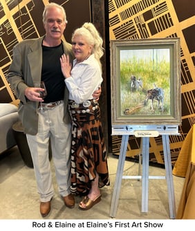 A photo of Rod and Elaine Lockard posing in front of Elaine's painting